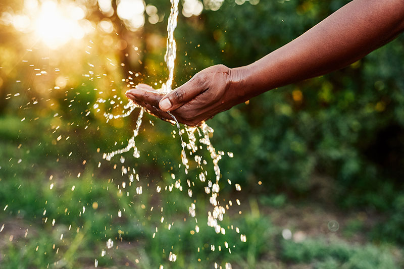 Water running into a cupped hand at sunset