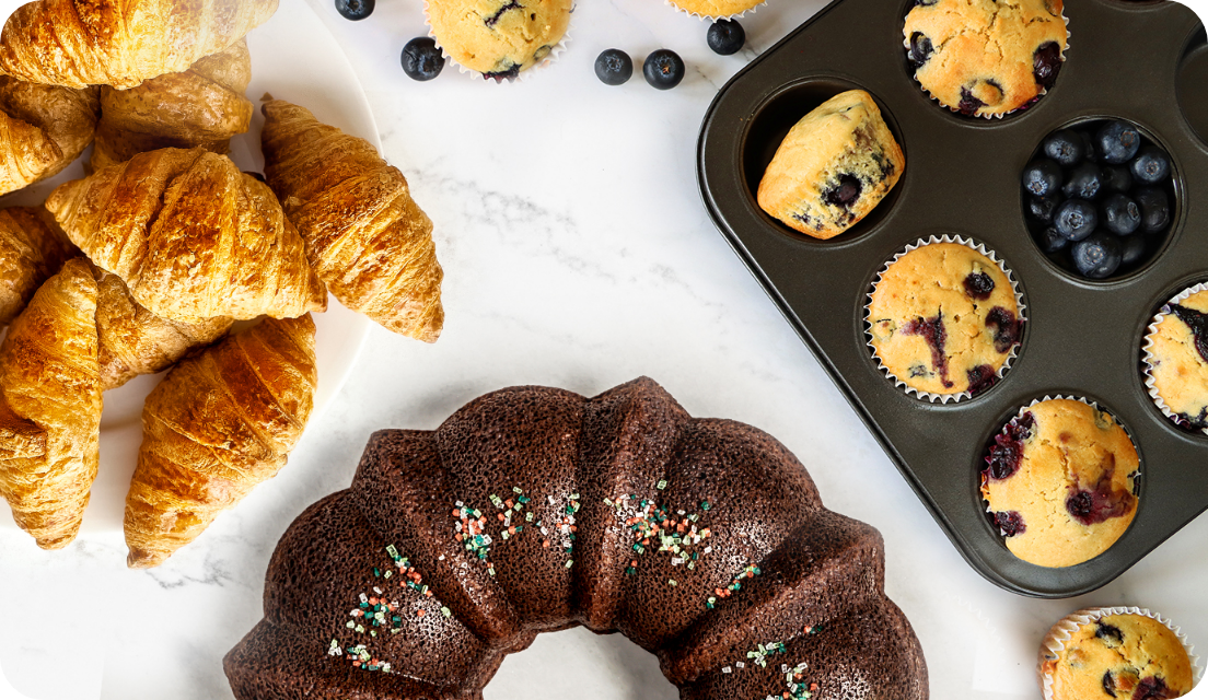 Bakery foods on a table, including croissants and blueberry muffins