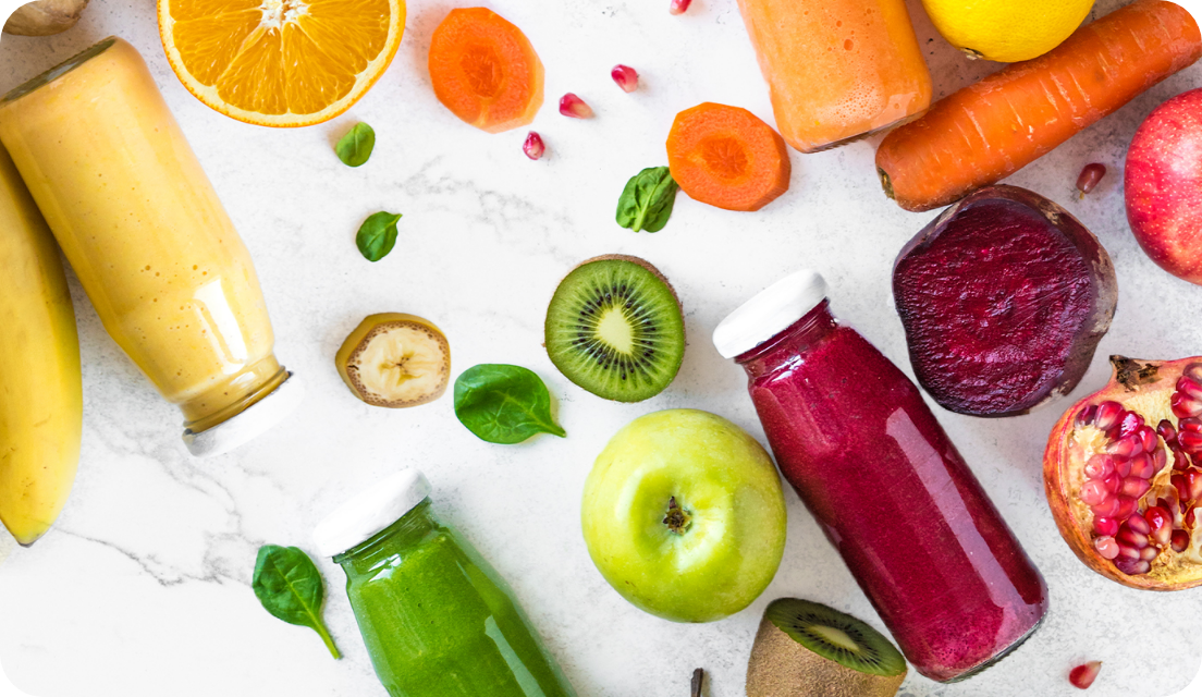 Fruit and vegetable beverages in reusable glass bottles on a table with fruits and vegetables