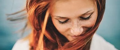 A woman with red hair looking down and smiling