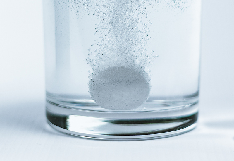 An effervescent tablet in a glass of water