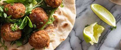 Some falafel in a wrap with a wedge of lime