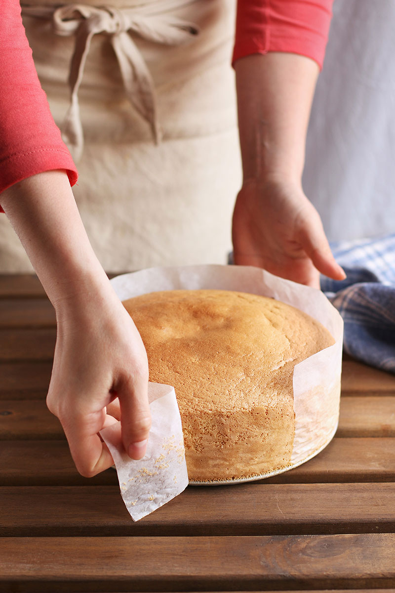 A woman taking a freshly baked cake from oven