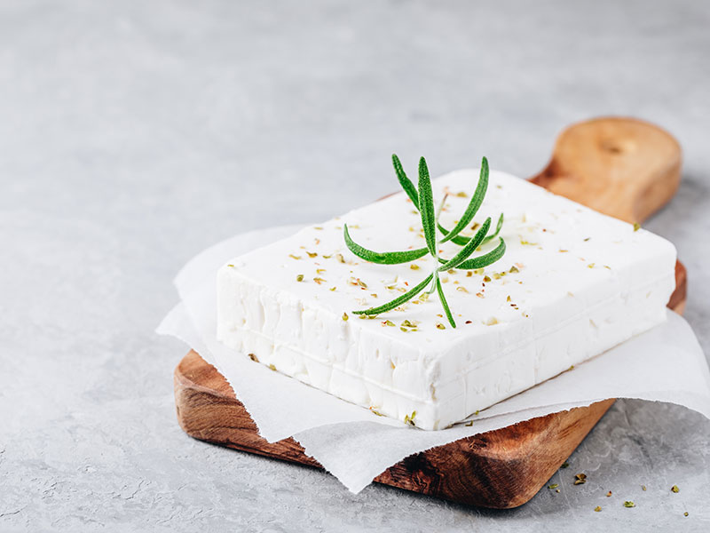 A block of garnished Brie on a chopping board