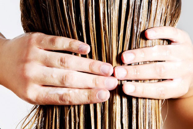 Rear view of woman applying conditioner to her hair