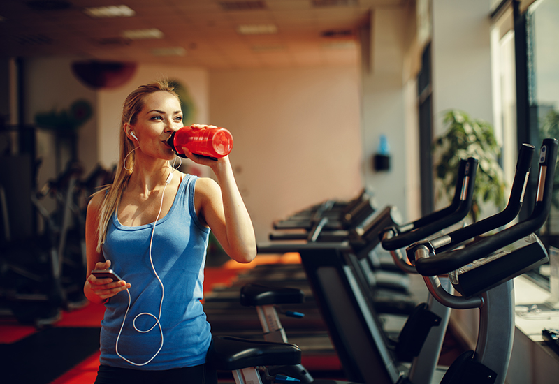 A girl in the gym drinking from a water bottle