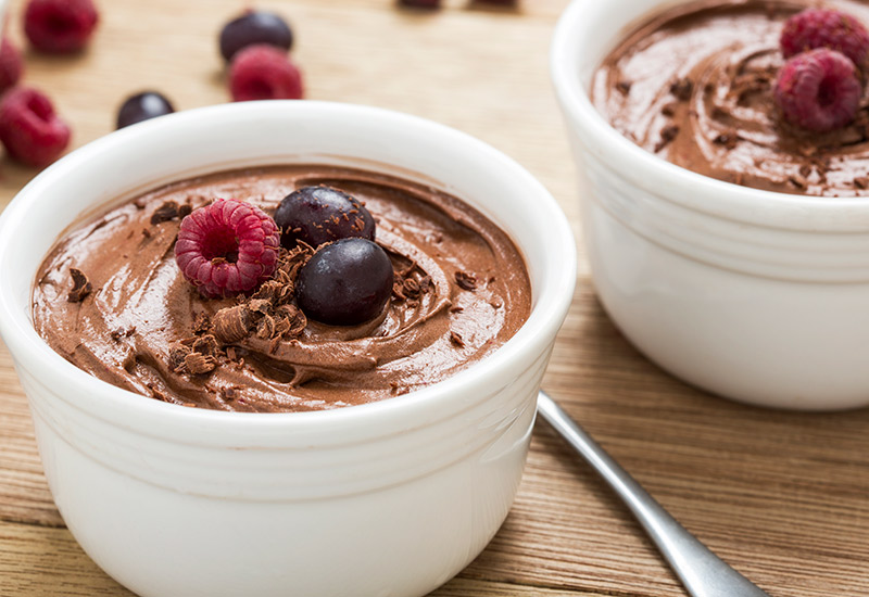 A chocolate dessert with fruit on top in a white bowl