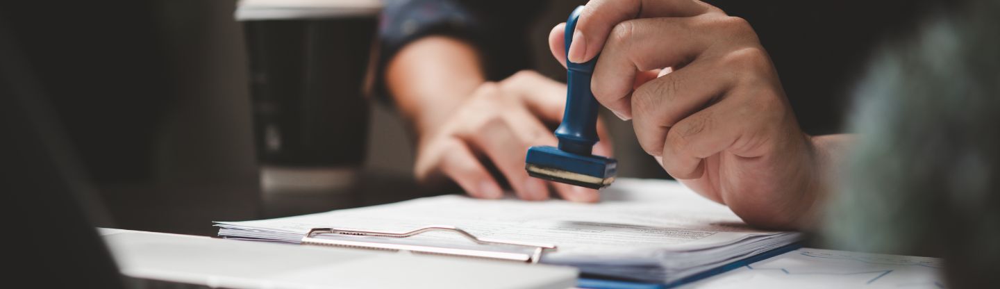 Close up of hands stamping a paper on a clip board for accreditation