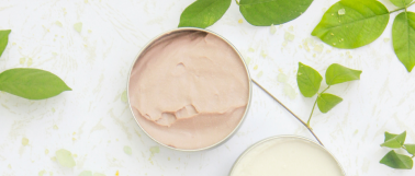 img title Blue light skincare products sit on a marble table top surrounded by green leaves