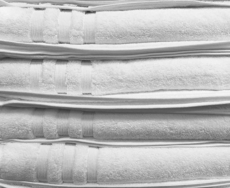 Four clean white towels folded and stacked on top of one another