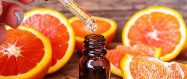 Grapefruit slices with oil being dropped into a small bottle