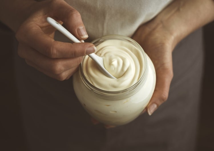 Hands holding a glass jar of homemade yogurt