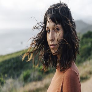 Woman with flowing locks atop a hill